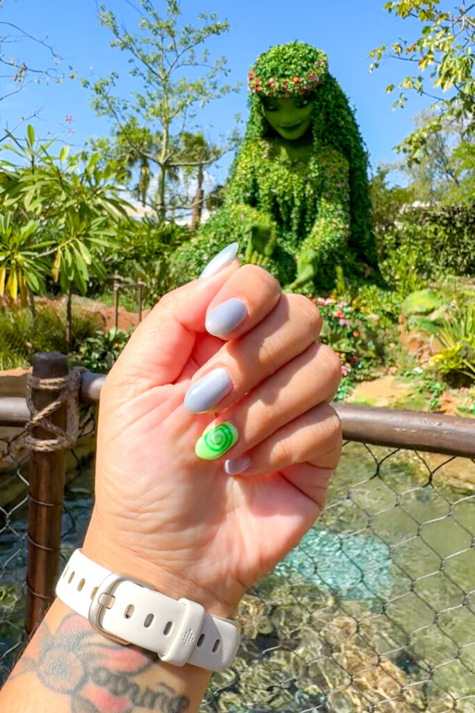 Close-up of Moana-inspired nails with Moana topiary at EPCOT in the background