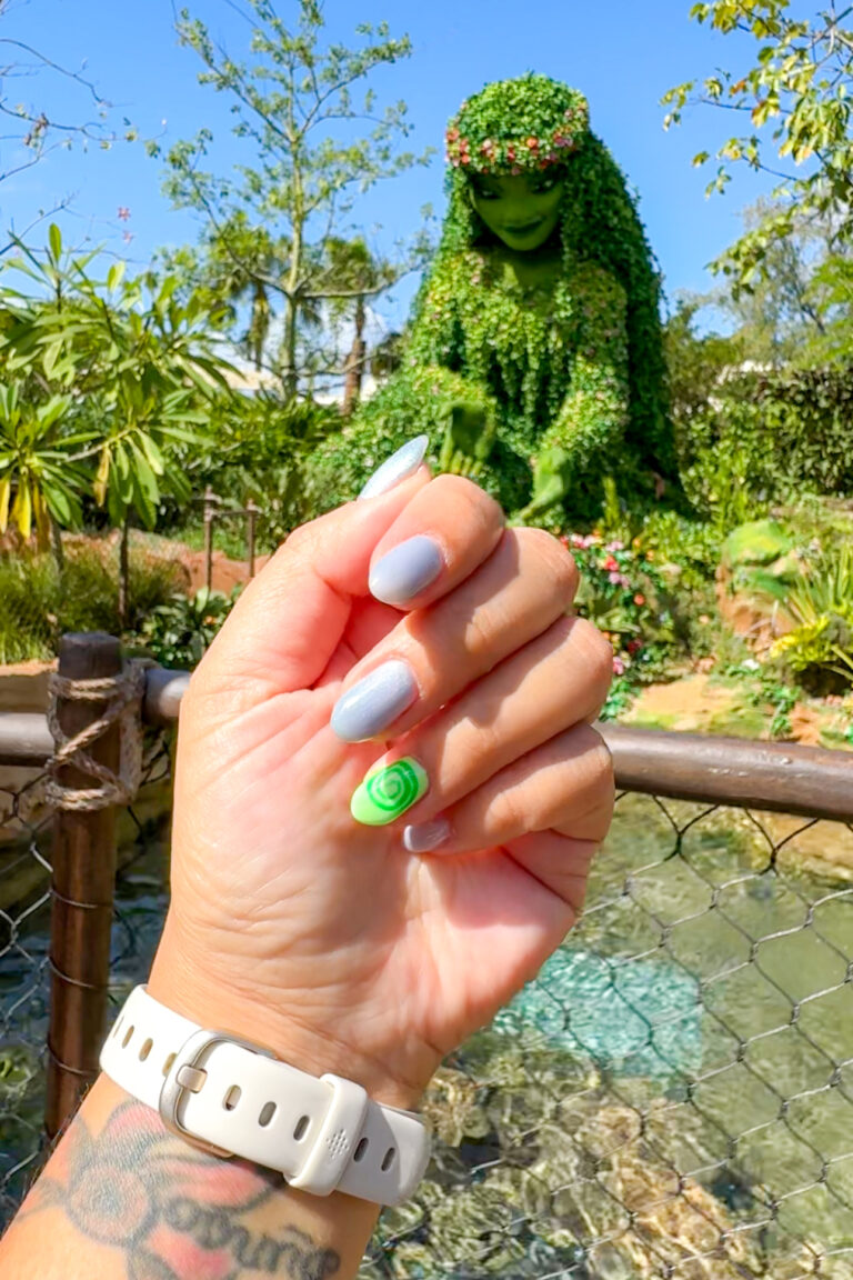 Close-up of Moana-inspired nails with Moana topiary at EPCOT in the background
