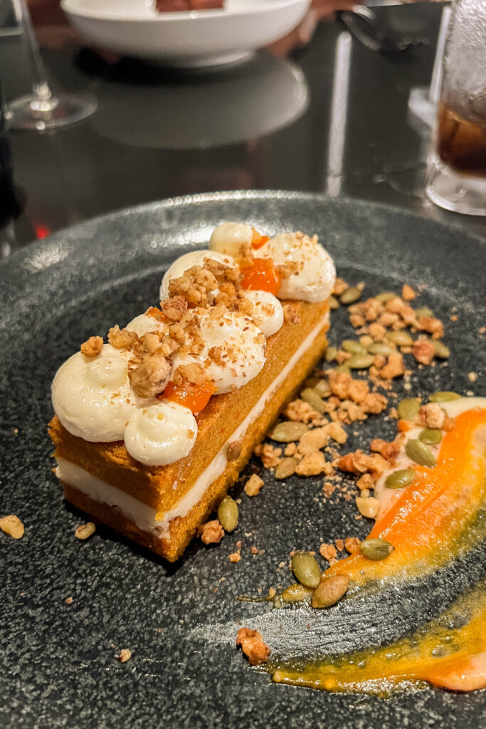 Carrot cake dessert served on a dark grey plate from Space 220 restaurant located in Disney's Epcot