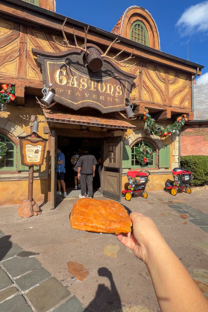 Holding the crème brûlée croissant outside Gaston’s Tavern at Magic Kingdom